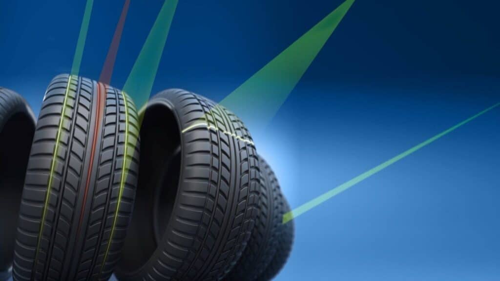 Mehrere Reifen werden mit grünen Laserlinien abgetastet, um Profilgeometrie und Rundlauf für die Qualitätskontrolle zu prüfen.