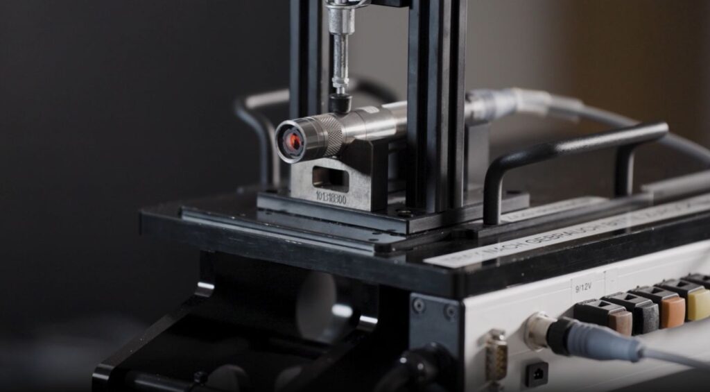 Laser module on a laser classification test bench with a multi-axis positioning unit and connected control unit.classes laser module
