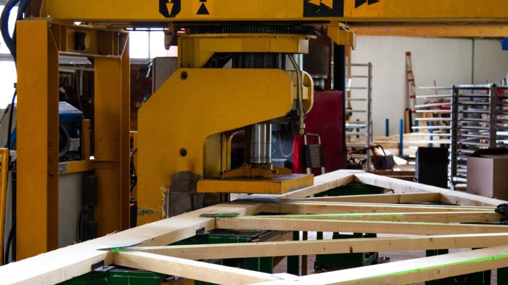 C-press in nail plate truss manufacturing with laser projection for precise positioning of wooden components.